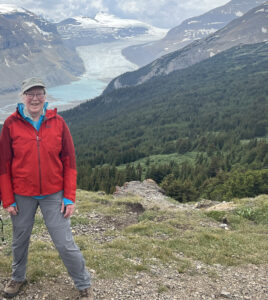 Maureen Muldoon in a red jacket with mountains and a glacier in the background