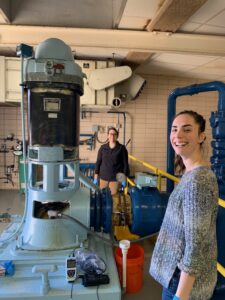 Woman in foreground with a machine. Person in back 