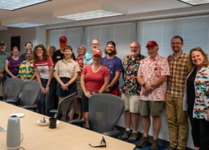 Jim poses for a photo surrounded by colleagues at a staff retirement event.